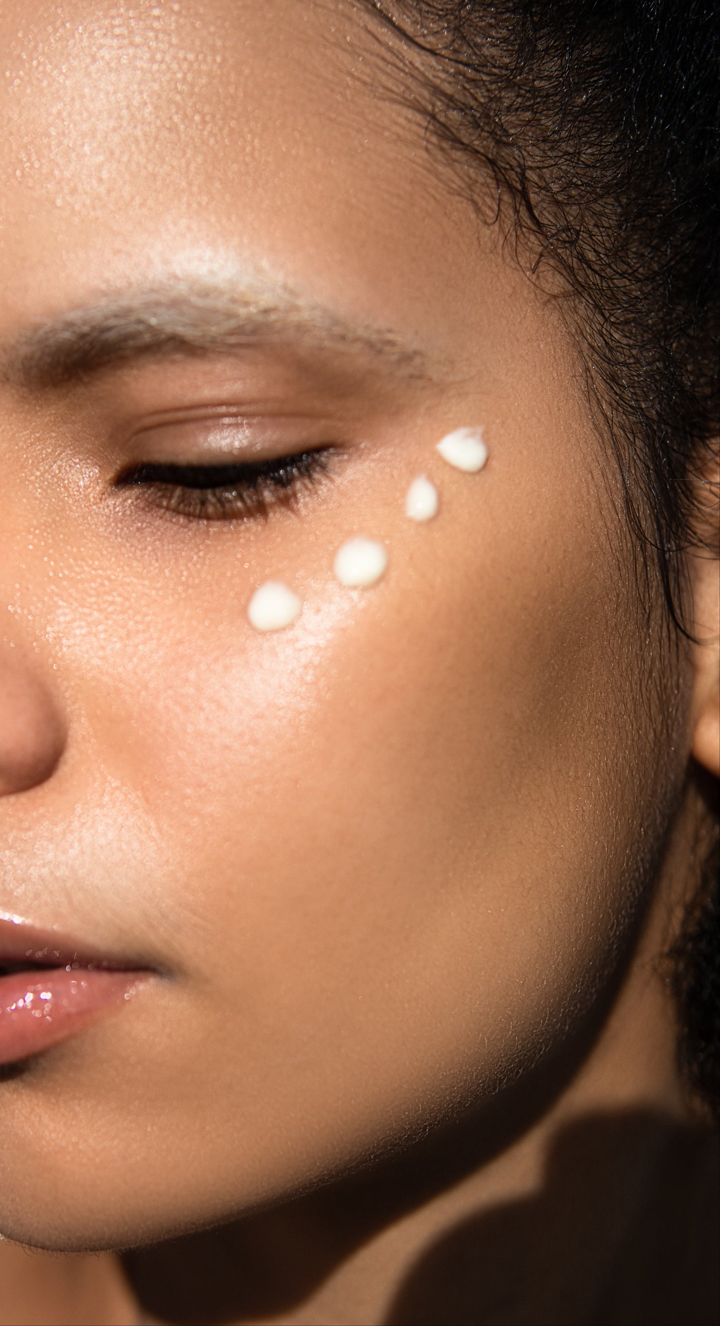 Close-up of a woman's face with a skincare product on her cheek